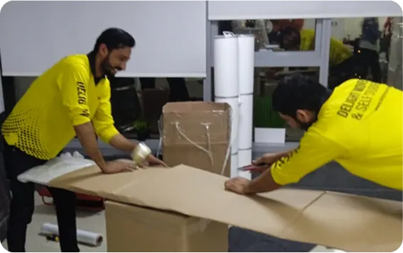 Movers packing office furniture with protective sheets in Abu Dhabi