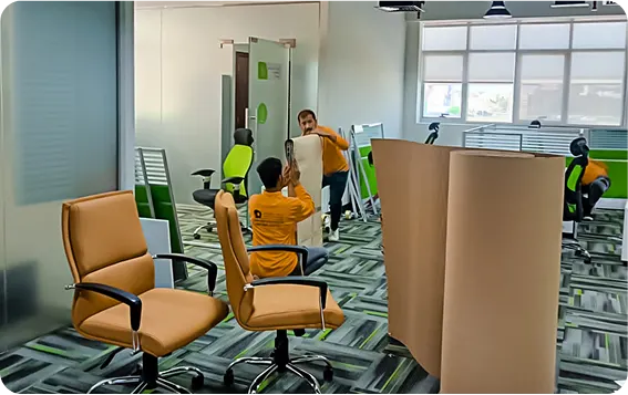 Movers wrapping office chairs and workstations during an office relocation